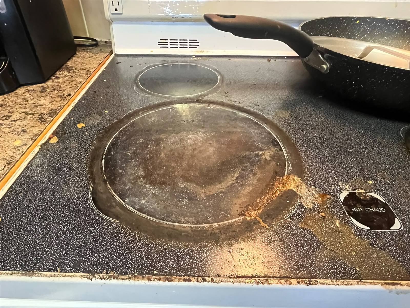 Glass stovetop covered in burnt-on grime before a SurfAway clean